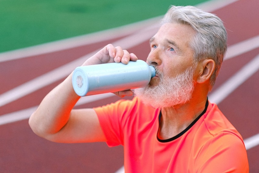 Man die water uit een bidon drinkt op eens sportveld